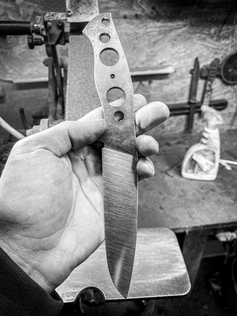 knife maker holding an unfinished handmade knife during the workshop process